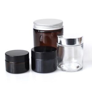 assorted cosmetic jars including amber glass jar, clear glass jar and black plastic cream containers with screw caps for skincare packaging